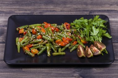 Yeşil fasulye, kırmızı kiraz domates susam siyah plaka ile pişmiş