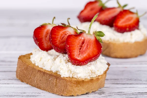 Zwei Sandwiches aus roter Erdbeere, weißem Quark und Brot auf dem weißen Holztisch, Nahaufnahme — Stockfoto