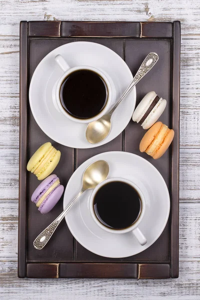 Две чашки кофе, ложки и пирожные из макарон на подносе на белом деревянном столе. Концепция образа жизни. Вид сверху — стоковое фото