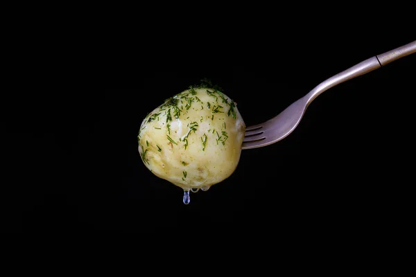 Gaffel med kokt unga potatis med dill och olja på en svart bakgrund — Stockfoto