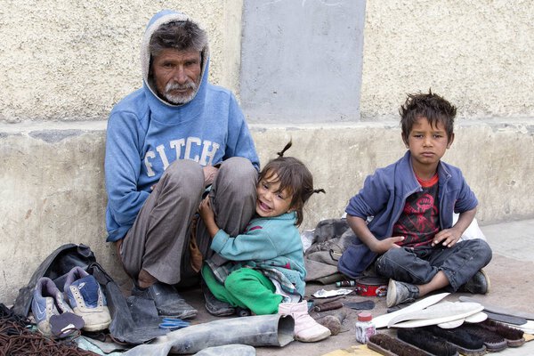Beggar family begs for money from a passerby in Leh. India