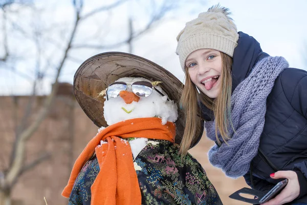 Feliz chica joven está tomando fotos de selfie con un muñeco de nieve —  Fotos de Stock