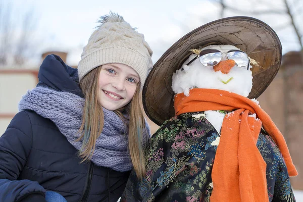 Chica joven feliz con un muñeco de nieve, de cerca —  Fotos de Stock