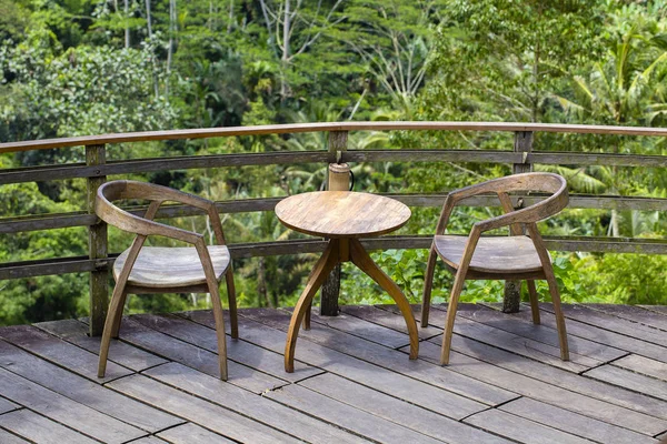 Houten tafel en twee stoelen op de achtergrond van de tropische bomen in het eiland Bali, Indonesië — Stockfoto