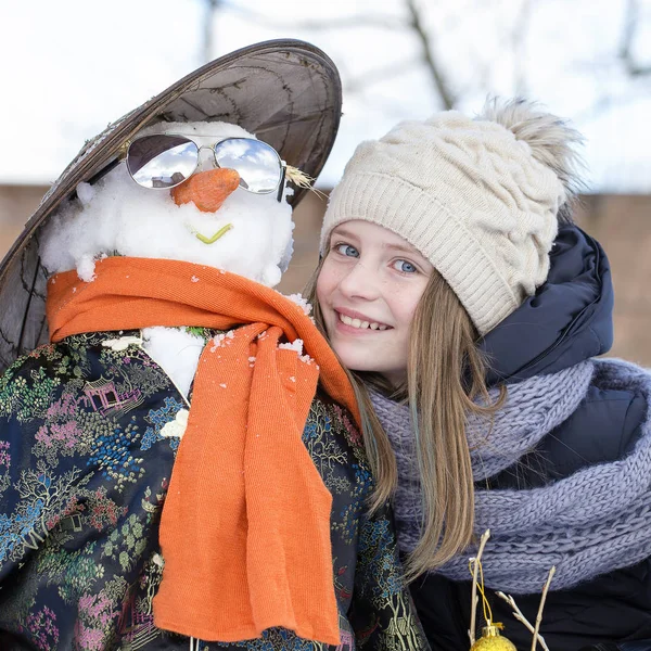 Chica joven feliz con un muñeco de nieve, de cerca —  Fotos de Stock