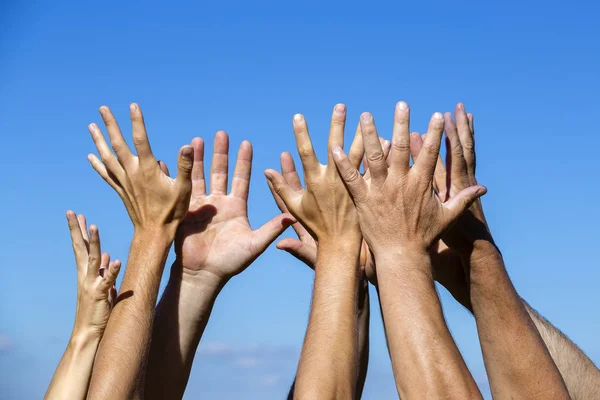 Grupo levantando las manos contra el fondo azul del cielo, de cerca —  Fotos de Stock