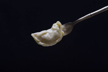 Ukrayna ve Rus yemekleri - vareniki veya köfte patates püresi veya süzme peynir üzerinde siyah bir zemin üzerine bir kaşık ile