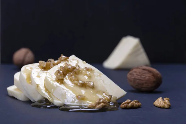 Suluguni cheese, walnut and honey on black slate platter — Stock Photo, Image