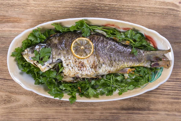 Carpa de pescado frito en plato sobre fondo de madera, vista superior — Foto de Stock