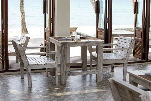 Mesa e cadeiras de madeira em café vazio ao lado da água do mar na praia, Tailândia — Fotografia de Stock