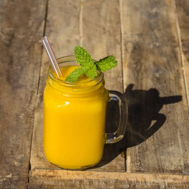 Taze organik mango sallamak içinde cam kupa üzerinde ahşap masa, yakın çekim