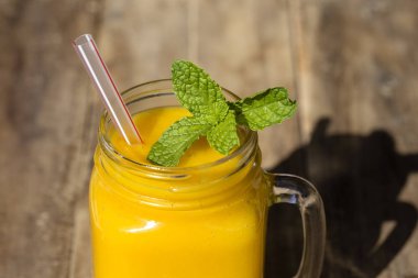 Taze organik mango sallamak içinde cam kupa üzerinde ahşap masa, yakın çekim