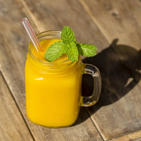 Frischer Bio-Mango-Shake im Glasbecher auf Holztisch, Nahaufnahme — Stockfoto