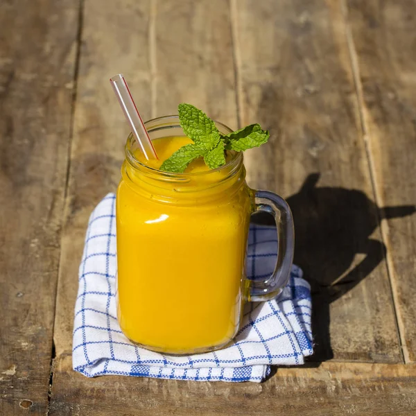 Agiter la mangue bio fraîche dans une tasse en verre sur une table en bois, fermer — Photo