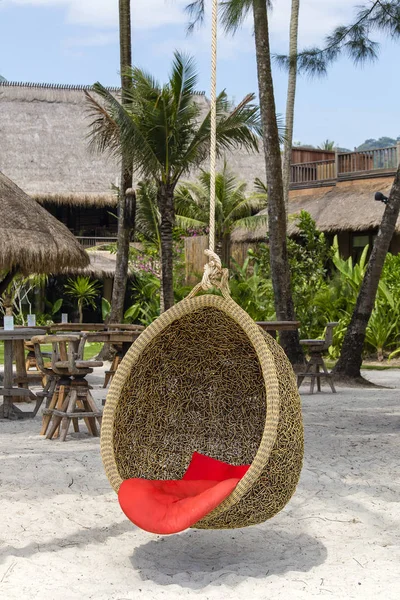 Columpio de mimbre con una almohada colgada en una palma de coco junto al mar en la playa de arena. Isla Koh Kood, Tailandia —  Fotos de Stock