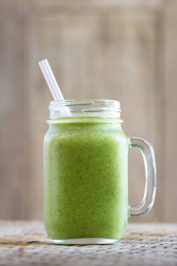 Avokado, muz, dereotu, brokoli ve bal cam kupa ahşap masa üzerinde gelen taze organik smoothies. Yakın çekim
