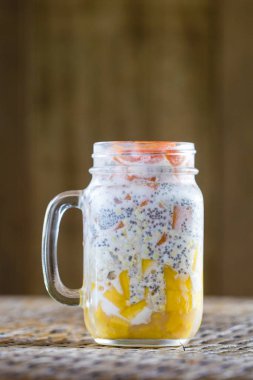 Sağlıklı gıda, chia tohum puding mango, yeşil buğday, papaya, yulaf gevreği, Hindistan cevizi sütü ve müsli, vitamini ile cam bardağa Servis Kahvaltı. Sabah Tayland
