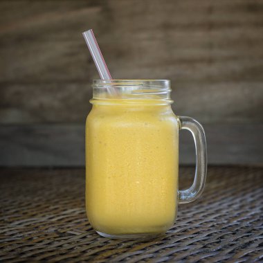 Taze organik mango sallamak içinde cam kupa üzerinde ahşap masa, yakın çekim