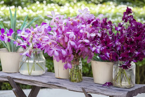 Bouquets orchid flowers in the tropical yard on a wooden table — Stock Photo, Image