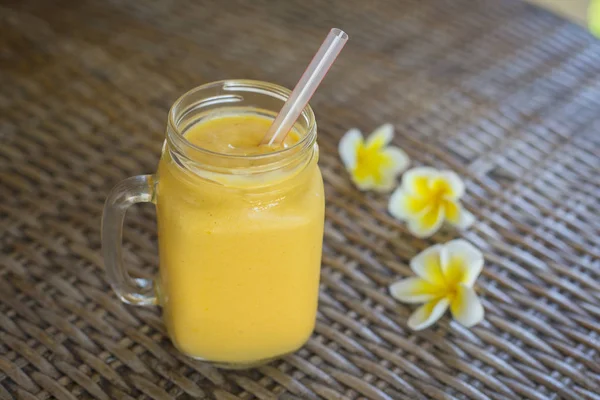 Fresh organic mango shake in glass mug on wooden table, close up — Stock Photo, Image