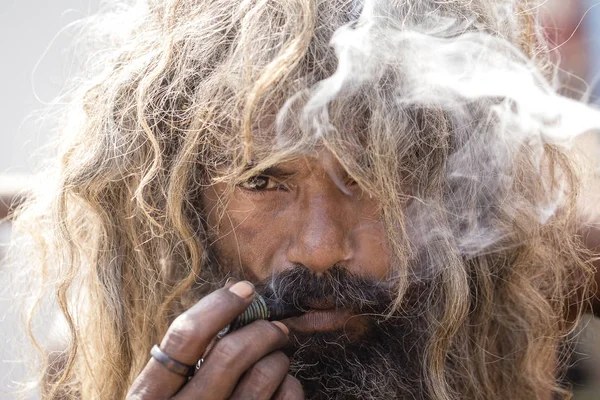 Sadhu hindú fumando ganja, marihuana, con chile en los ghats del río Ganges en Varanasi, India. De cerca. — Foto de Stock