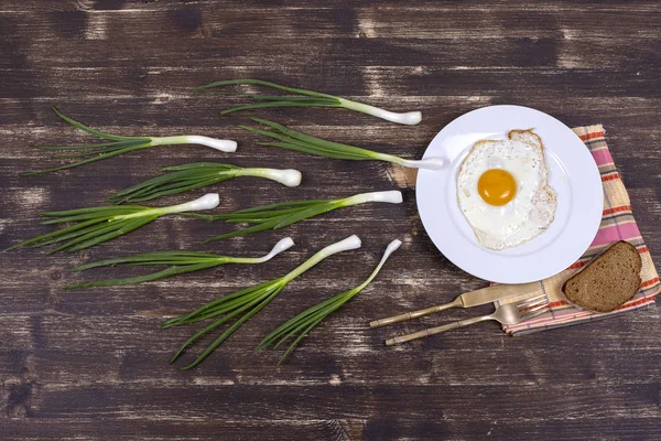 Τηγανητό αυγό, πράσινο σχοινόπρασο, λευκή πλάκα, μαχαίρι και πιρούνι μοιάζουν στο σπερματικό ανταγωνισμό. Σπερματοζωάριο επιπλέουν ωάριο. Κοντινό πλάνο — Φωτογραφία Αρχείου