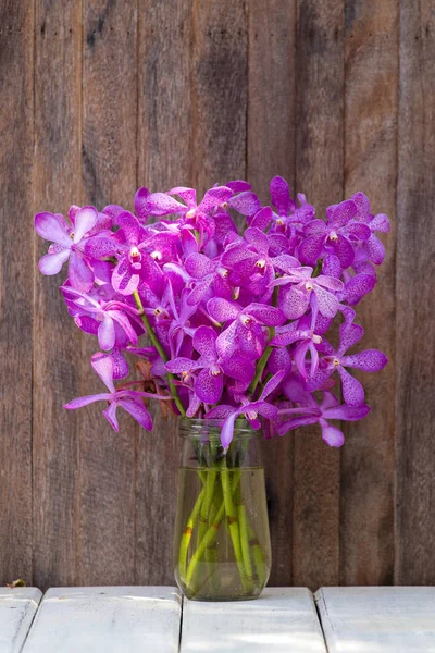 Bouquets flores de orquídea no quintal tropical em uma mesa de madeira — Fotografia de Stock