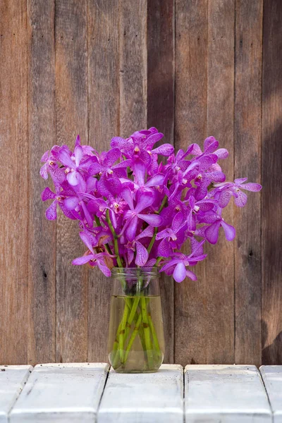 Buketter orkidé blommor i den tropiska trädgården på ett träbord — Stockfoto