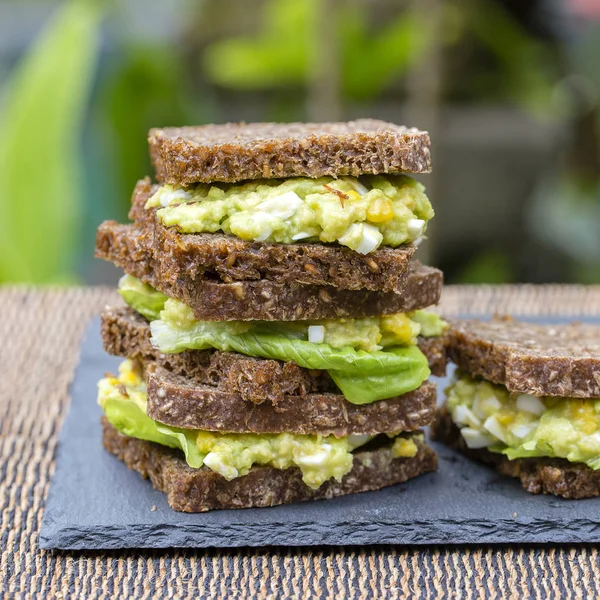 Sandwich con aguacate y huevo escalfado - concepto de desayuno saludable — Foto de Stock