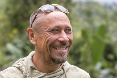 İnsanlar ve yaşam tarzı kavramı. Portre mutlu orta yaşlı tıraşsız adamla neşeli gülümseme yeşil doğa arka planı açık, yakın çekim