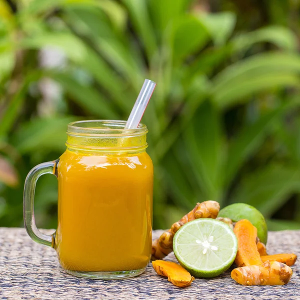 Energy tonic drink with turmeric, ginger, lemon and honey in glass mug, nature background — Stock Photo, Image