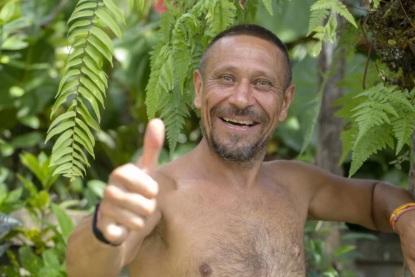 Koncepcja ludzie i styl życia. Szczęśliwy średnim wieku zarośnięty mężczyzna z pogodnym uśmiechem odkryty na tle zieleni, portret z bliska — Zdjęcie stockowe