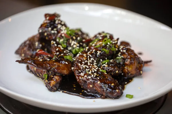 Baked chicken wings with sesame seeds and sweet chili sauce, close up — Stock Photo, Image