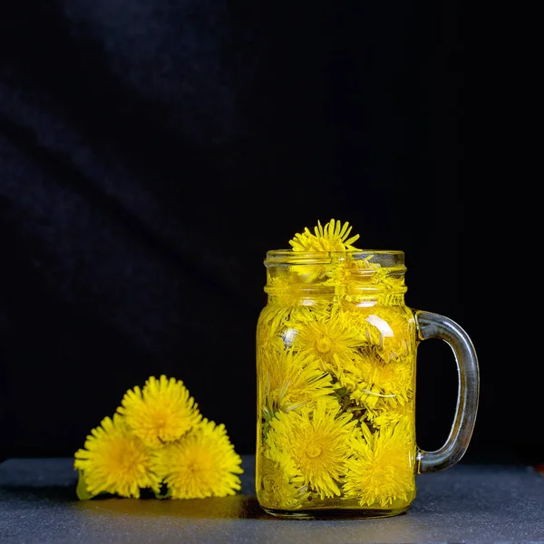 Pissenlit thé fleur jaune boisson dans une tasse en verre sur fond noir. Concept de saine alimentation — Photo