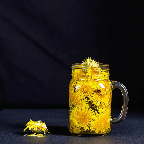 Pissenlit thé fleur jaune boisson dans une tasse en verre sur fond noir. Concept de saine alimentation — Photo