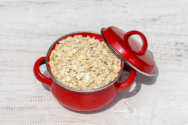 Red pan with dry oat flakes — Stock Photo, Image
