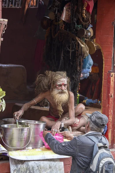 Sadhu, heiliger Mann füttert die hungrigen Menschen in der Nähe eines pashupatinath Tempels, kathmandu, nepal — Stockfoto