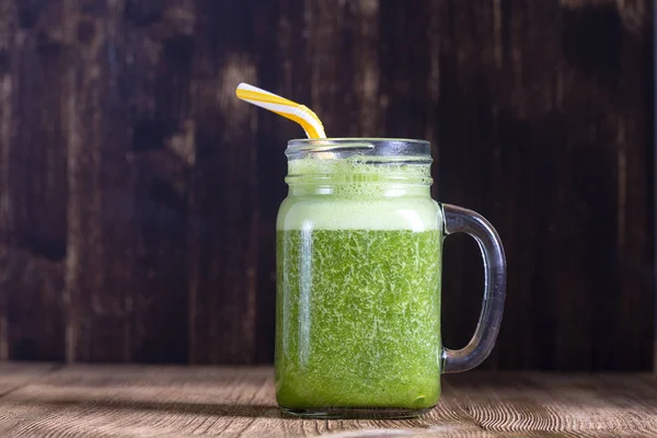 Fresh green smoothie from avocado, banana, parsley and honey on wooden background, close up — Stock Photo, Image