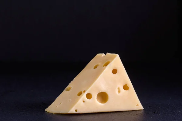 Stück Käse auf schwarzem Hintergrund — Stockfoto