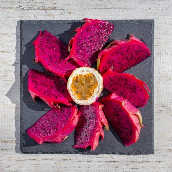 Exotic pink dragon fruit cut and passionfruit on background close up. Sweet tropical fruit, juicy pitaya and passion fruit cut