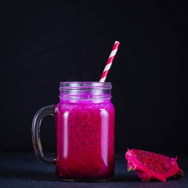 Dragon meyve, muz, mango ve papaya cam kupa siyah arka plan üzerine taze smoothies. Sağlıklı beslenme kavramı