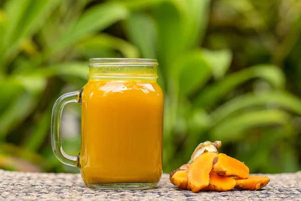 Τονωτικό ποτό ενέργειας με κουρκούμη, τζίντζερ, λεμόνι και μέλι σε γυάλινη κούπα, φύση φόντο — Φωτογραφία Αρχείου