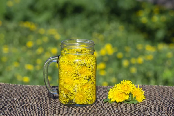 Paardebloem gele bloem thee drinken in glazen mok op tafel, buitenshuis. Begrip van gezond eten — Stockfoto