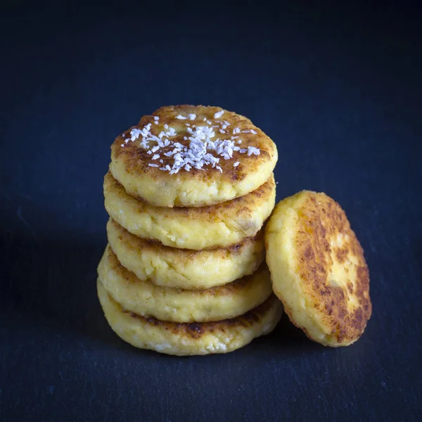 Cottage cheese pancakes with raisins, coconut chips, syrniki on black background — Stock Photo, Image