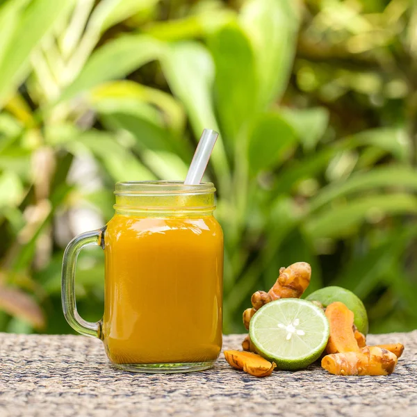 Energy tonic drink with turmeric, ginger, lemon and honey in glass mug, nature background — Stock Photo, Image