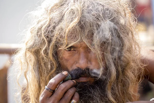 Sadhu hindú fumando ganja, marihuana, con chile en los ghats del río Ganges en Varanasi, India. De cerca. —  Fotos de Stock