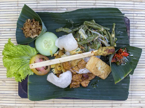 Nasi Campur Μπαλί. Μπαλινέζικο πιάτο ρύζι στον ατμό με ποικιλία από πιάτα πλευρά. Κοντινό πλάνο. Ασιατικό φαγητό, Ουμπούντ, Μπαλί, Ινδονησία. Royalty Free Φωτογραφίες Αρχείου