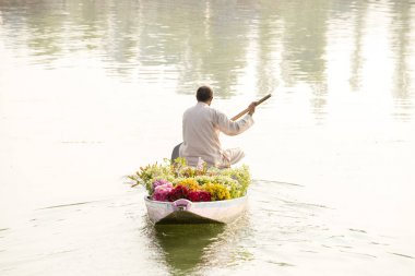 Yerel halkın Shikara, küçük bir tekne ulaşım Dal Gölü Srinagar, Jammu and Kashmir devlet, Hindistan için kullanın. Bir adam bir buket çiçek bir tekne Satılık taşır.