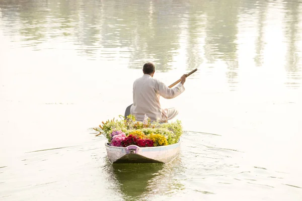 La gente local utiliza Shikara, un pequeño barco para el transporte en el lago Dal de Srinagar, Jammu y el estado de Cachemira, India. Un hombre lleva un ramo de flores para la venta en un barco . —  Fotos de Stock