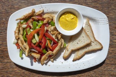 Kızarmış tavuk filetosu, sebzeli ve ekmekli, beyaz tabakta, yakın plan.